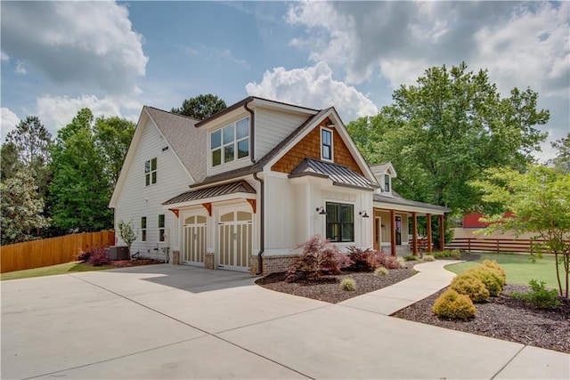 view of front of property featuring fence, board and batten siding, a porch, concrete driveway, and a standing seam roof