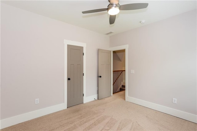 unfurnished bedroom with carpet flooring, a ceiling fan, baseboards, and visible vents