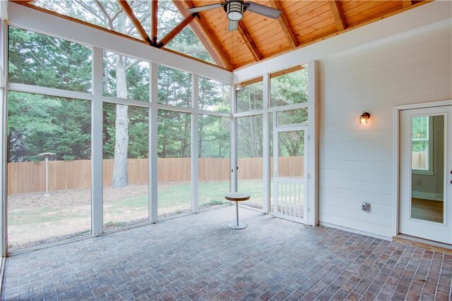 unfurnished sunroom with a healthy amount of sunlight, a ceiling fan, and beam ceiling