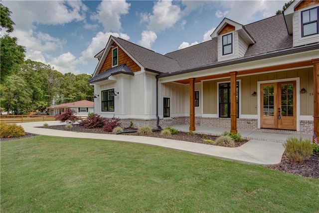 exterior space featuring board and batten siding, a porch, roof with shingles, brick siding, and a front lawn