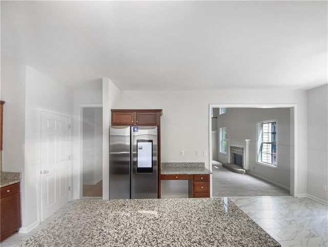 kitchen with stainless steel fridge, light carpet, and light stone counters