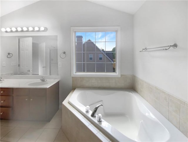 bathroom featuring tile patterned flooring, lofted ceiling, tiled tub, and vanity