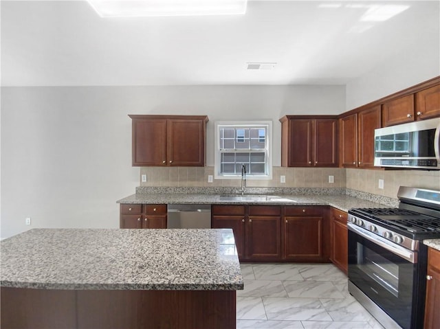 kitchen with a center island, light stone countertops, sink, and stainless steel appliances