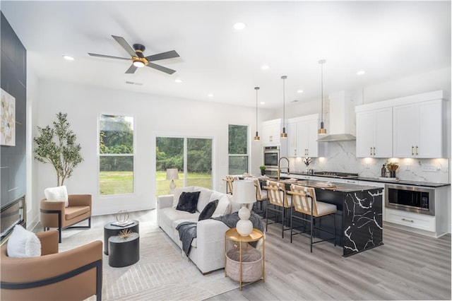 living room featuring ceiling fan, light hardwood / wood-style floors, and sink