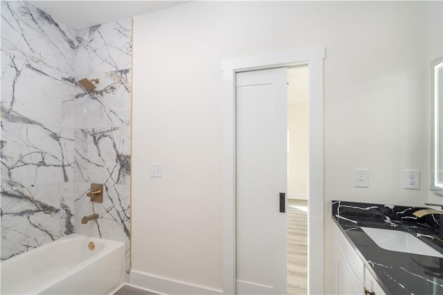 bathroom with hardwood / wood-style flooring, tiled shower / bath, and vanity