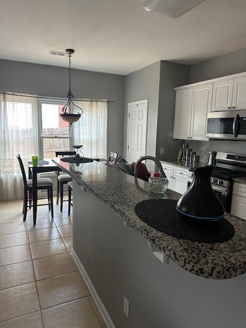280 Ridge Bluff Ln, Suwanee, GA 30024 - kitchen featuring appliances with stainless steel finishes, white cabinets, light tile patterned flooring, and stone countertops