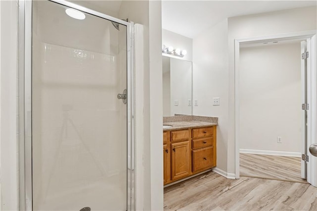 bathroom featuring a shower with shower door, hardwood / wood-style floors, and vanity