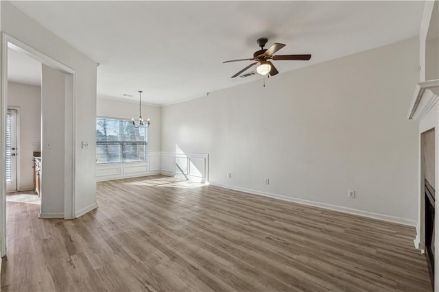 unfurnished living room featuring ceiling fan with notable chandelier and wood-type flooring