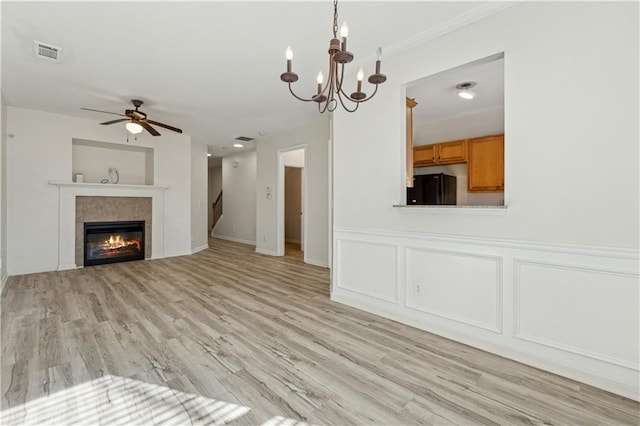 unfurnished living room featuring light wood-type flooring, ceiling fan with notable chandelier, and a tile fireplace