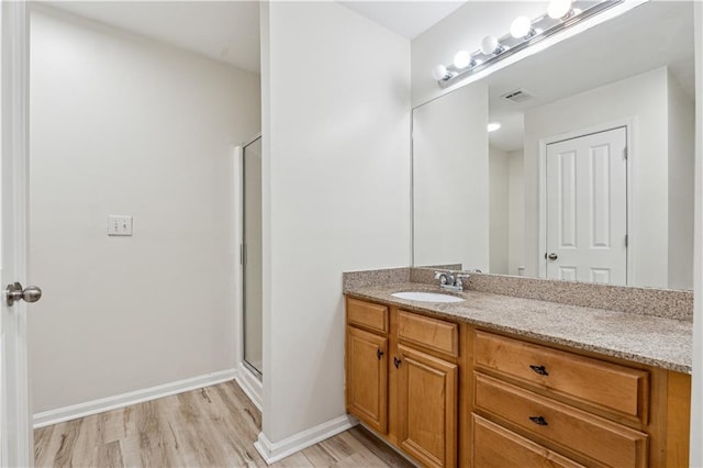 bathroom with a shower with door, hardwood / wood-style floors, and vanity