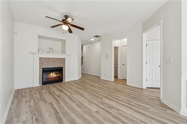 unfurnished living room featuring ceiling fan, a tile fireplace, and light hardwood / wood-style floors