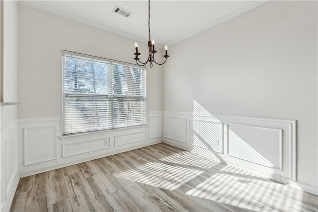 spare room featuring crown molding, light hardwood / wood-style floors, and a notable chandelier