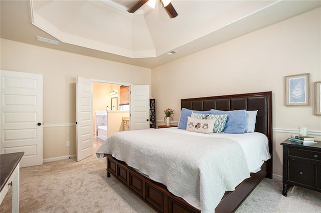 bedroom with light carpet, a raised ceiling, ensuite bath, and ceiling fan