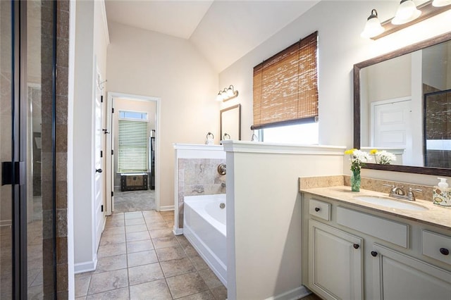 full bath with plenty of natural light, lofted ceiling, vanity, a garden tub, and tile patterned flooring