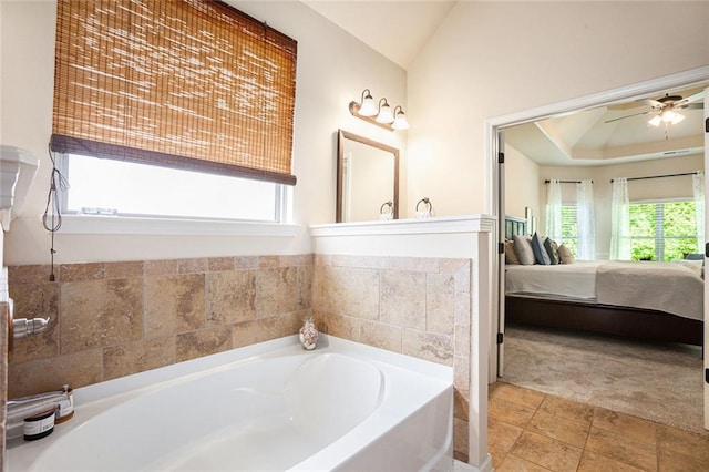 ensuite bathroom featuring healthy amount of natural light, a garden tub, ceiling fan, and lofted ceiling