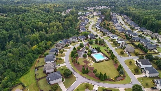 view of property location with a heavily wooded area, a pool area, and nearby suburban area