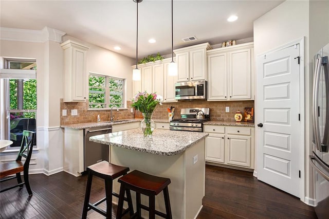 kitchen with appliances with stainless steel finishes, a sink, dark wood-type flooring, a center island, and recessed lighting