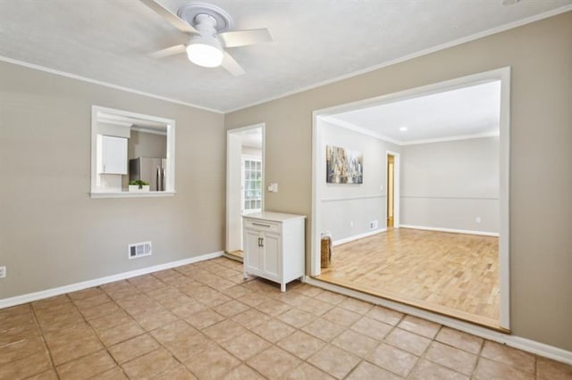 empty room with ornamental molding, ceiling fan, and light tile patterned floors