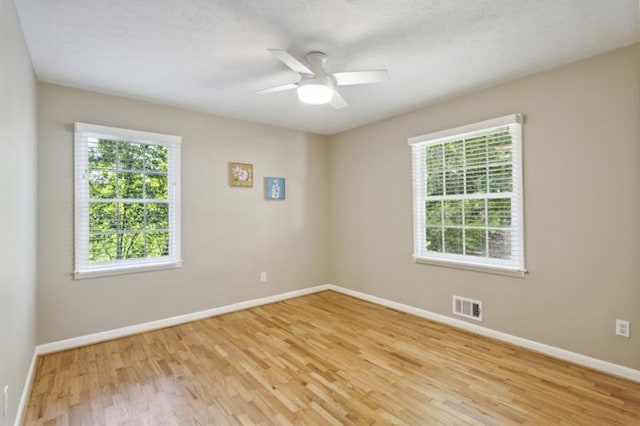 spare room featuring ceiling fan, light hardwood / wood-style floors, and a wealth of natural light