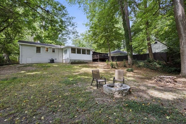 view of yard featuring a sunroom, cooling unit, and a fire pit