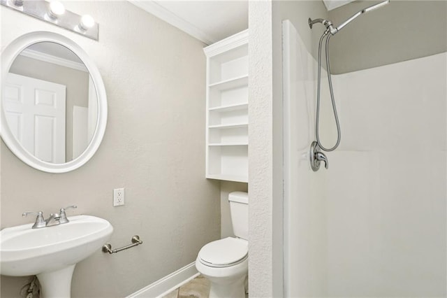 bathroom featuring toilet, ornamental molding, a sink, baseboards, and walk in shower