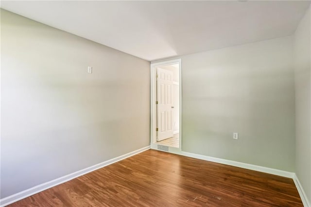 unfurnished room with baseboards, wood finished floors, and visible vents