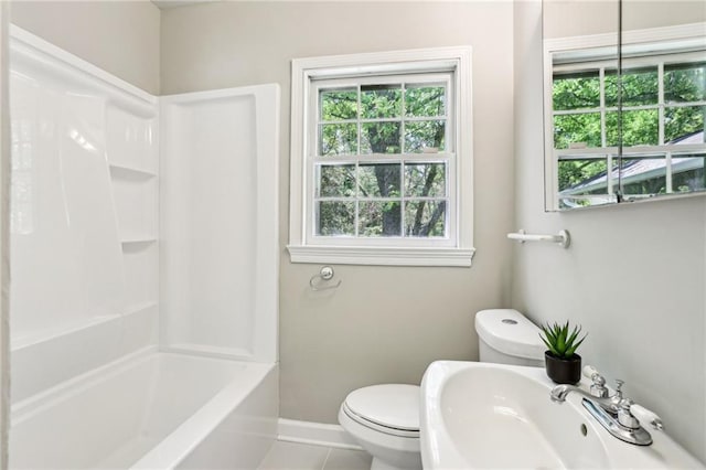 full bathroom featuring toilet, a healthy amount of sunlight, a sink, and baseboards
