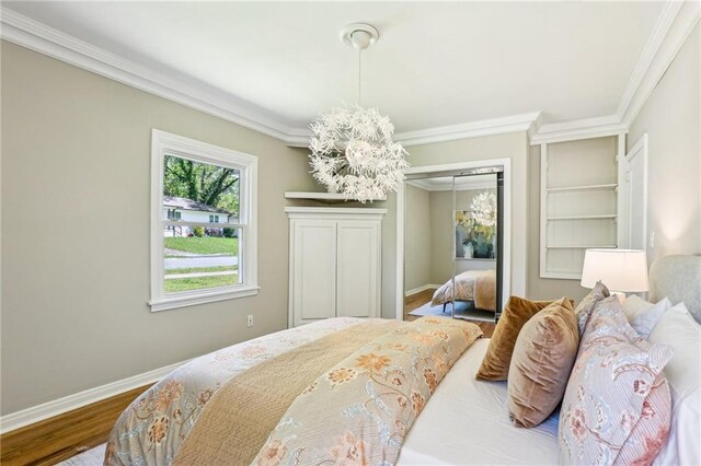 bedroom featuring baseboards, ornamental molding, wood finished floors, and a closet