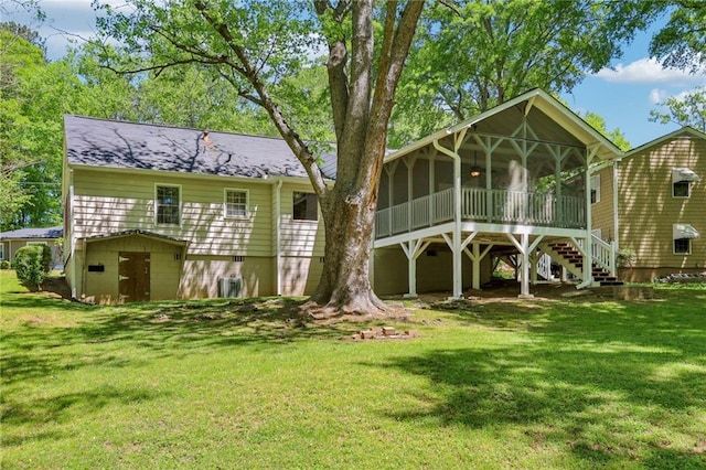 back of property featuring stairs, a storage shed, an outbuilding, a lawn, and a sunroom