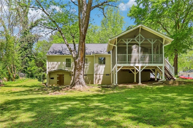 back of house with a lawn, a sunroom, stairs, and roof with shingles