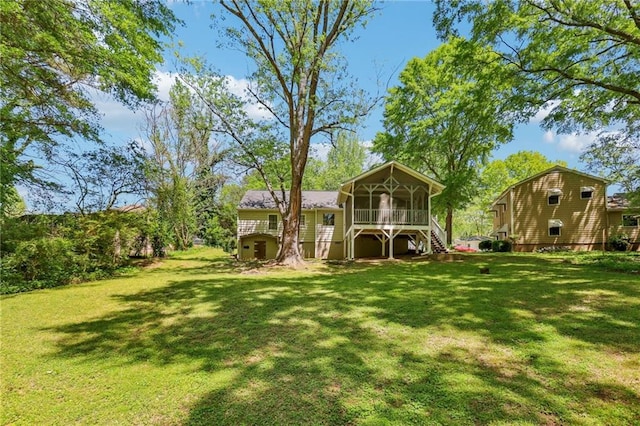back of property with a lawn, a sunroom, and stairway