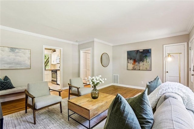 living area featuring baseboards, ornamental molding, light wood-style floors, and visible vents