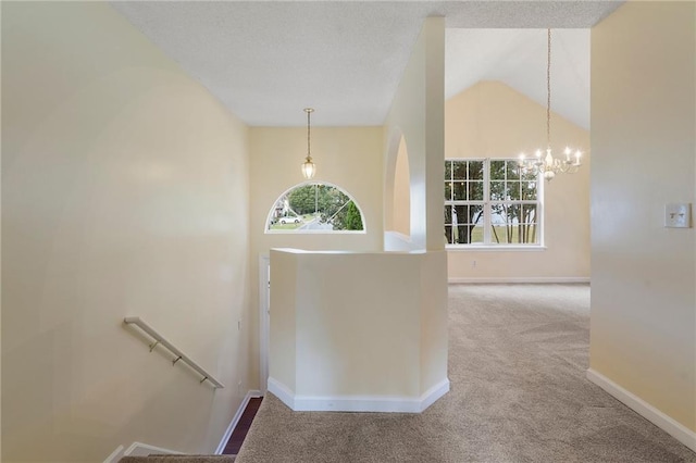 hall with a chandelier, carpet floors, and high vaulted ceiling