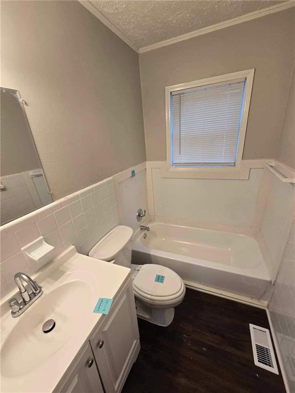 bathroom with vanity, a textured ceiling, hardwood / wood-style floors, toilet, and a tub