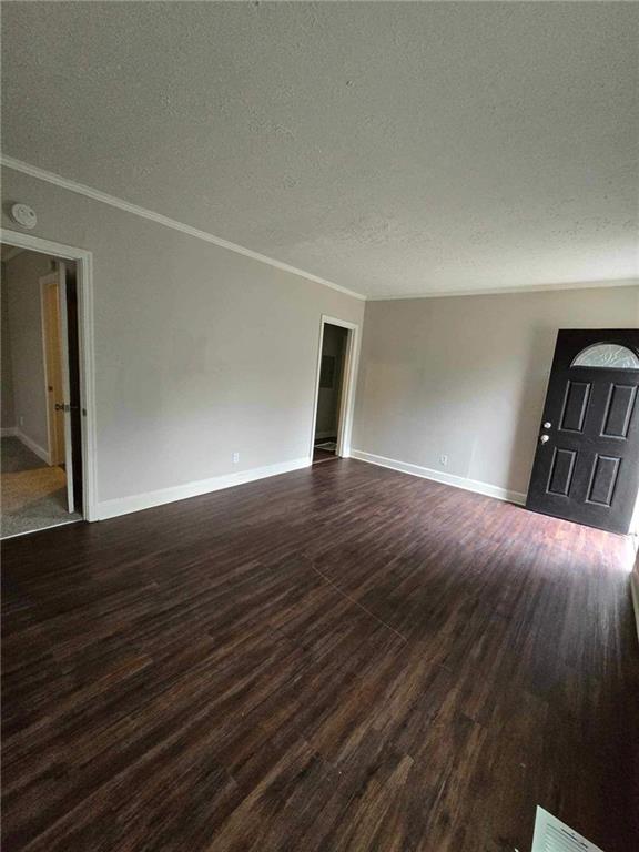 spare room with dark hardwood / wood-style flooring, a textured ceiling, and ornamental molding