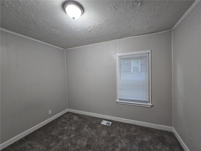 carpeted spare room with a textured ceiling, ornamental molding, and wood walls