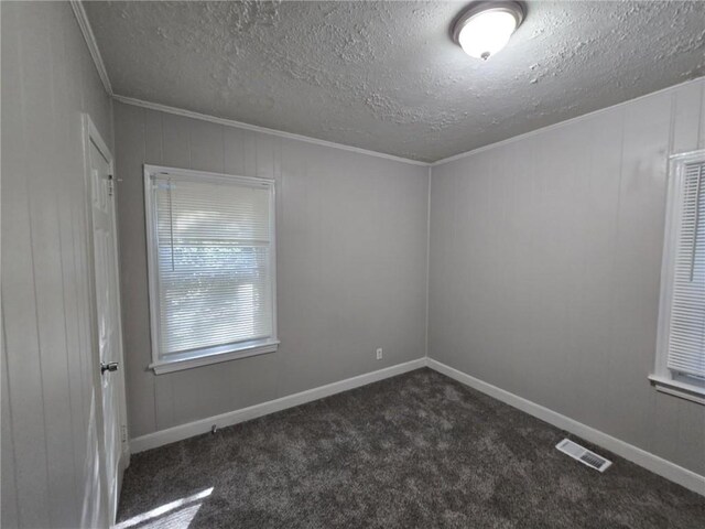 unfurnished room with crown molding, a textured ceiling, and dark colored carpet