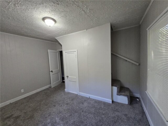 unfurnished bedroom with dark colored carpet, ornamental molding, a textured ceiling, and a closet