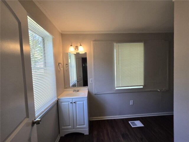 bathroom featuring visible vents, ornamental molding, wood finished floors, baseboards, and vanity