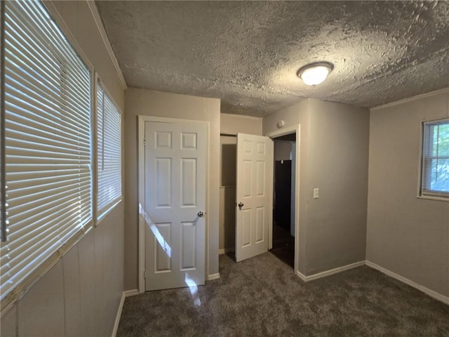 unfurnished bedroom featuring carpet flooring, a textured ceiling, and baseboards