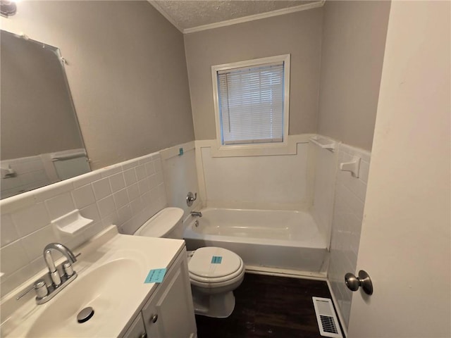 full bath featuring visible vents, toilet, a textured ceiling, wainscoting, and a bath