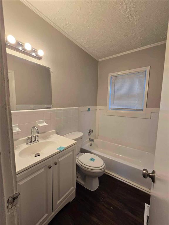 bathroom featuring a washtub, vanity, a textured ceiling, wood-type flooring, and toilet