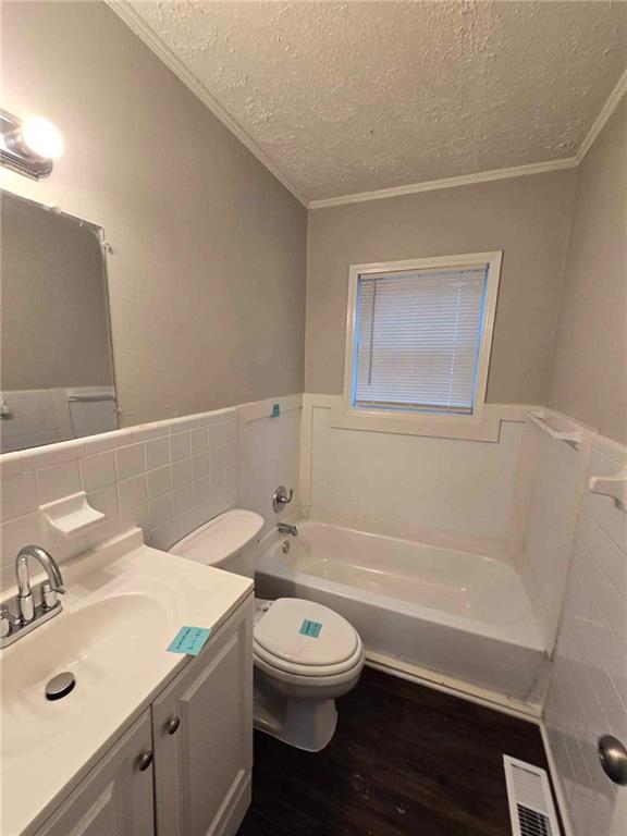 bathroom featuring vanity, a textured ceiling, hardwood / wood-style flooring, toilet, and a tub