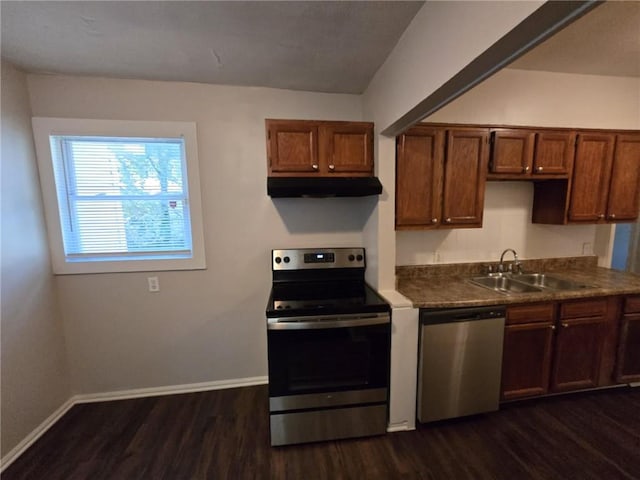 kitchen with a sink, baseboards, under cabinet range hood, stainless steel appliances, and dark wood-style flooring