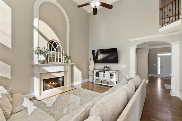 living room featuring decorative columns, a premium fireplace, a high ceiling, and hardwood / wood-style floors