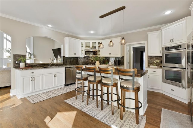 kitchen with dark hardwood / wood-style floors, kitchen peninsula, white cabinets, and appliances with stainless steel finishes