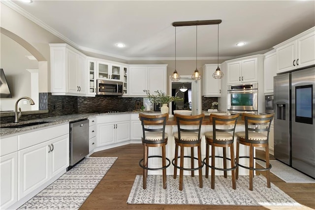 kitchen featuring appliances with stainless steel finishes, white cabinetry, sink, hanging light fixtures, and light stone countertops