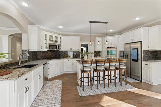 kitchen with sink, appliances with stainless steel finishes, white cabinetry, light stone countertops, and a kitchen island