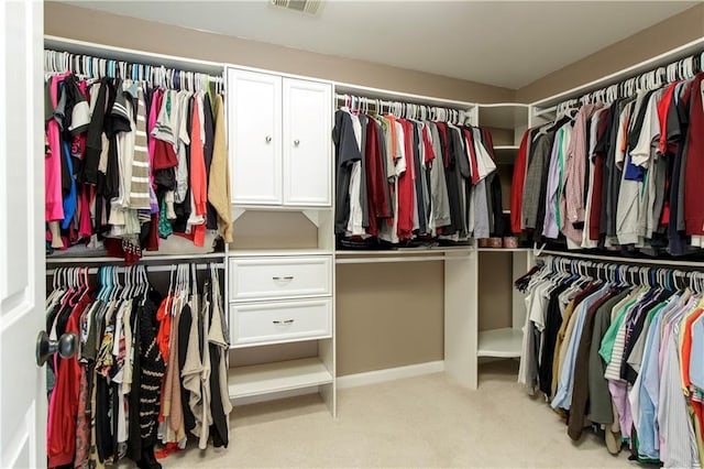 walk in closet with light colored carpet