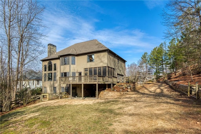 back of house featuring a wooden deck, a yard, and a sunroom